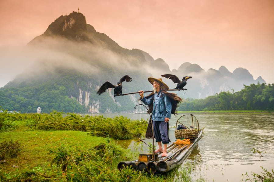 Paisaje con un pescador en su lancha en el rio Cormoran en Yangshuo